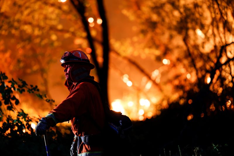 A firefighter monitors flames at the River Fire near Grass