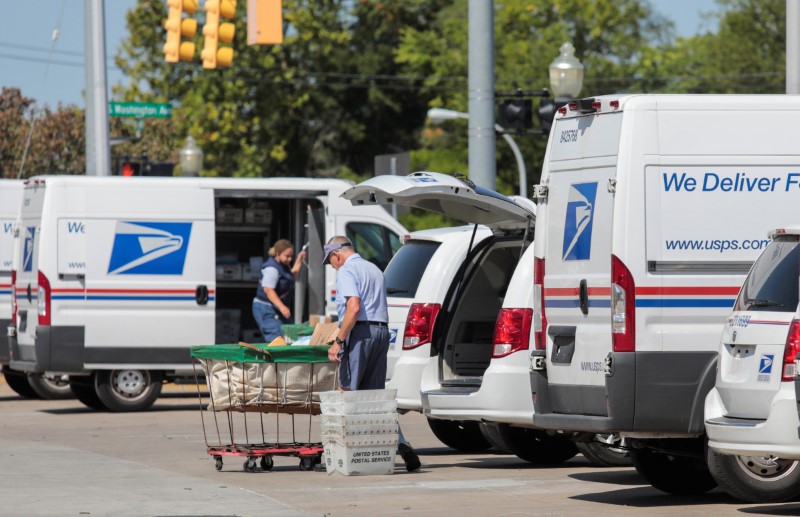 United States Postal Service (USPS) workers load mail into delivery
