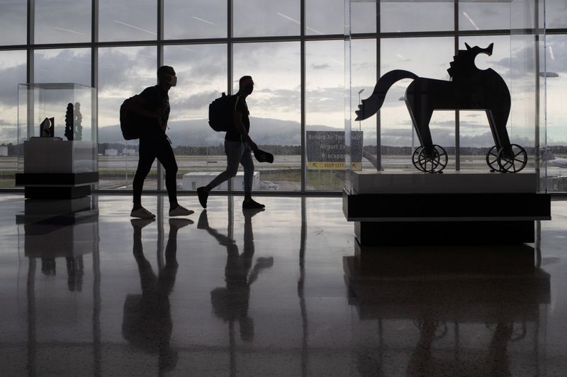 Passengers walk past artwork between terminals at IAH George Bush