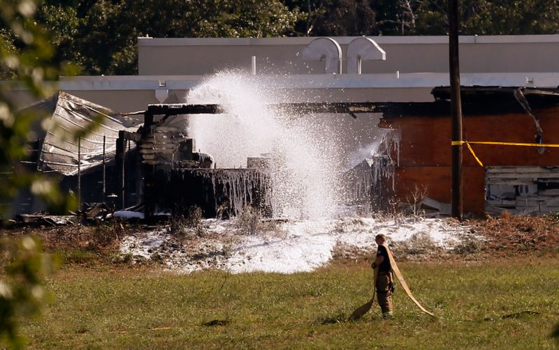 Firefighters spray foam on the smoking wreckage of a U.S.