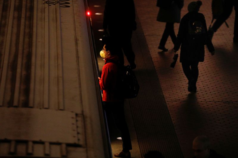 A person wearing a mask steps onto a subway car