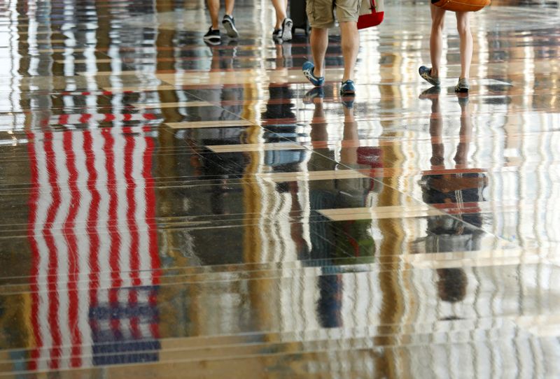 A U.S. flag is reflected on the floor as passengers