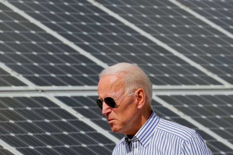 FILE PHOTO: Joe Biden walks past solar panels in Plymouth,