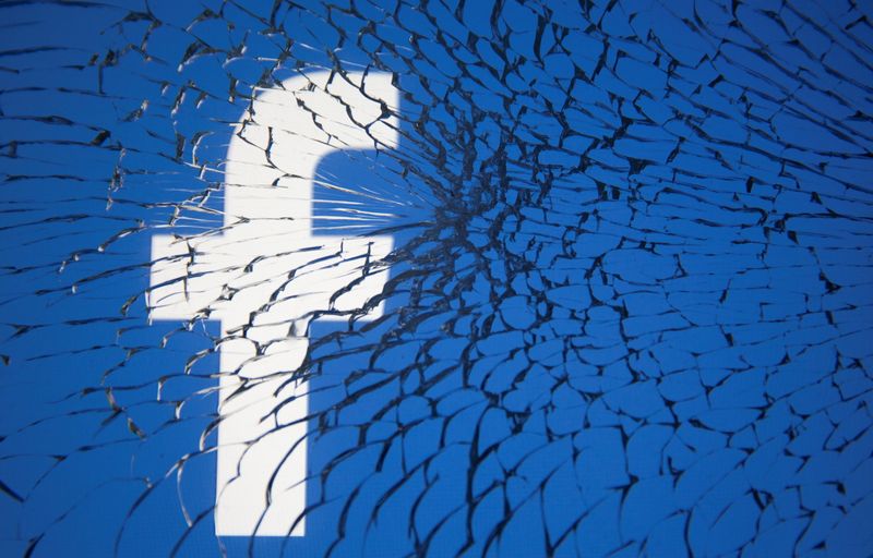 FILE PHOTO: Facebook logo is displayed through broken glass in