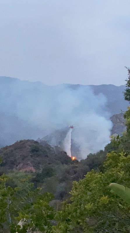 A helicopter tries to put out a brush fire in
