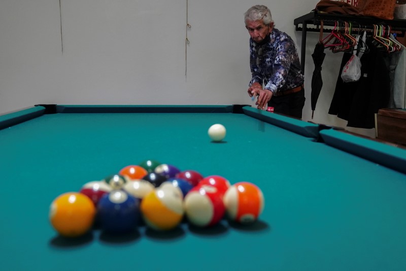 A man shoots the cue ball to break as he