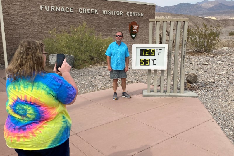 Tourists pose by thermometer in Death Valley
