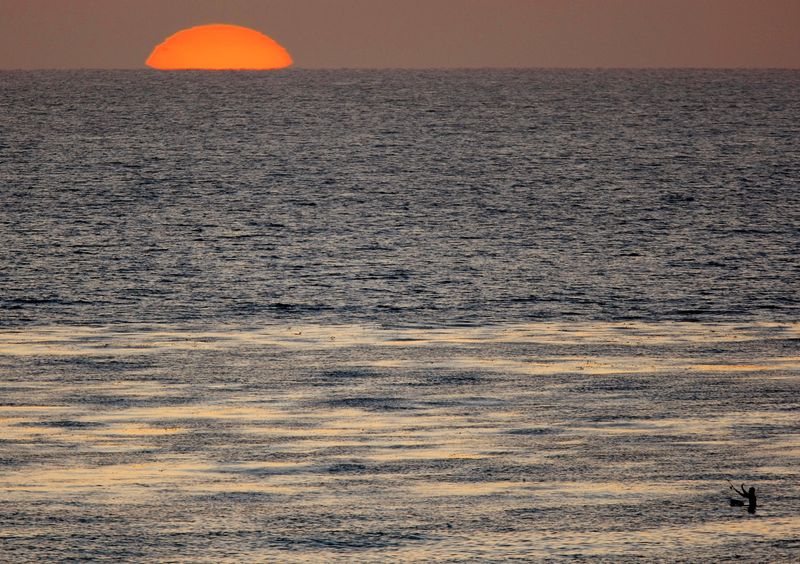 FILE PHOTO: The sun sets as a fisherman casts his