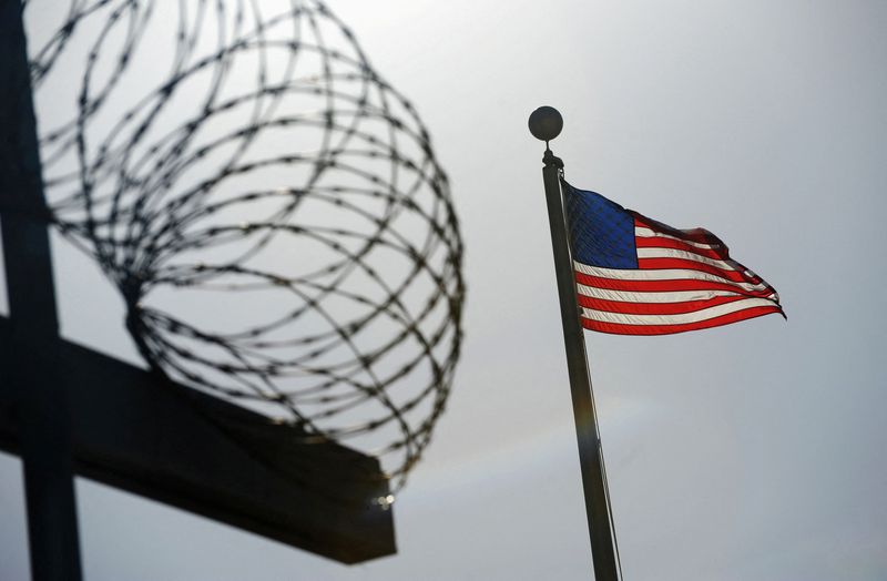 FILE PHOTO: A U.S. flag flies above a razorwire-topped fence
