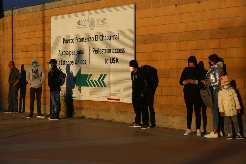 FILE PHOTO: Migrants queue at the El Chaparral border crossing