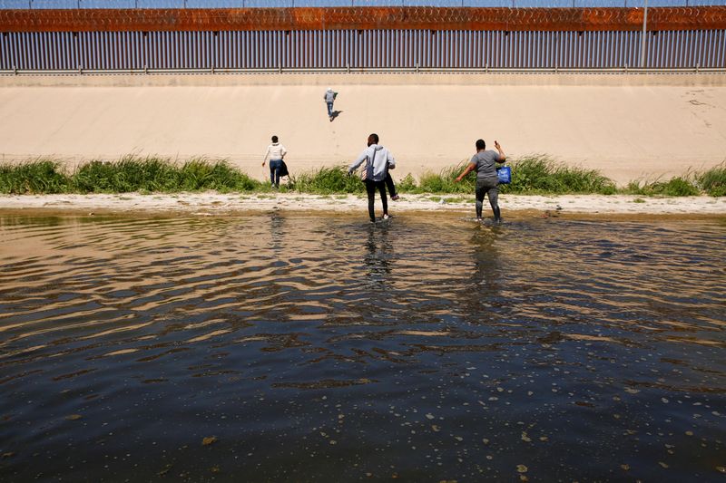 FILE PHOTO – Asylum-seeking migrants walk out of the Rio