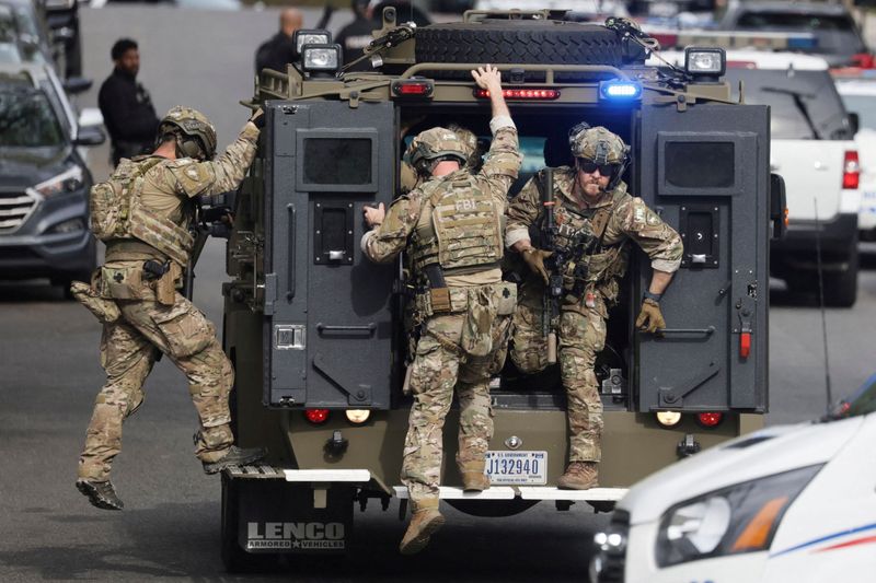 An FBI tactical team deploys from an armored vehicle at