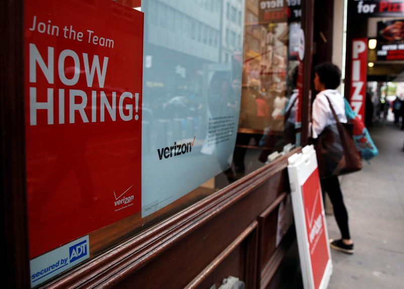 A “Now Hiring” sign is posted on a Verizon store