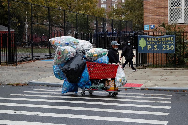 A man with a protective face mask walks with recyclables