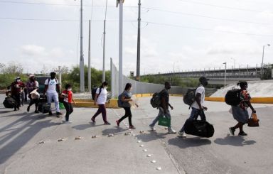 Migrants walk across the Reynosa-Hidalgo International Border Bridge after being