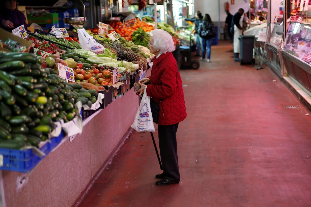 A woman looks at fruits and vegetables at a market
