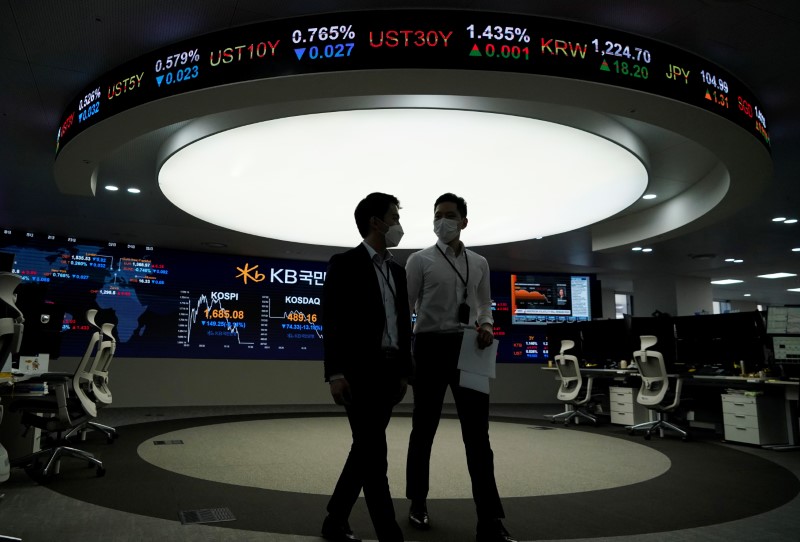 FILE PHOTO:  Currency dealers walk past an electronic board