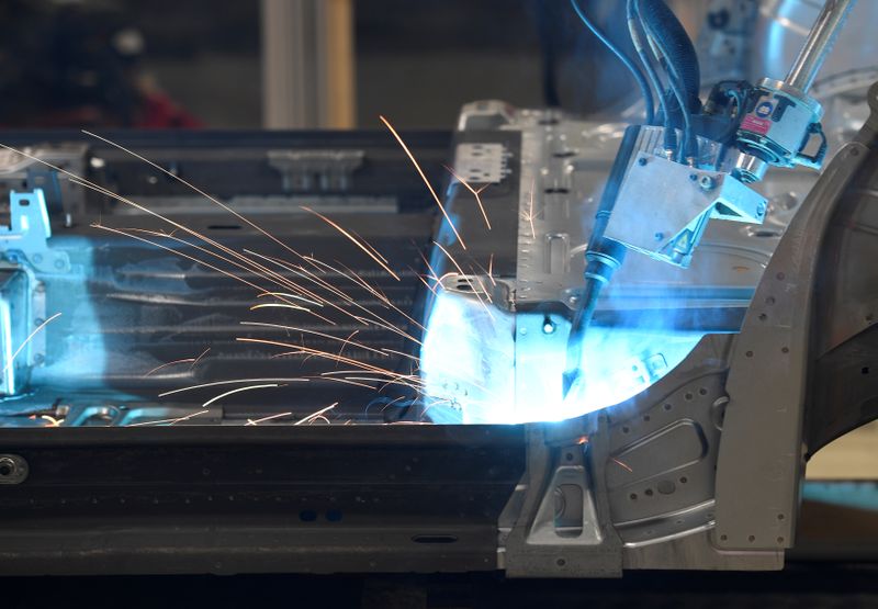 A robot welds car components in a production line at