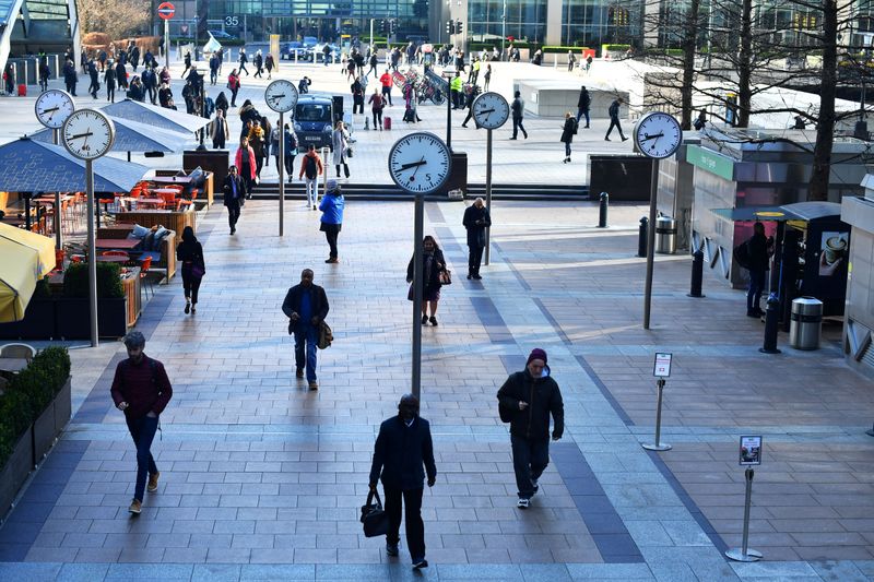 FILE PHOTO: Commuters walk through Canary Wharf in London