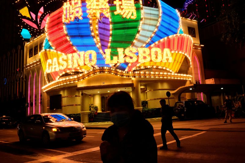 People wearing masks walk in front of Casino Lisboa before