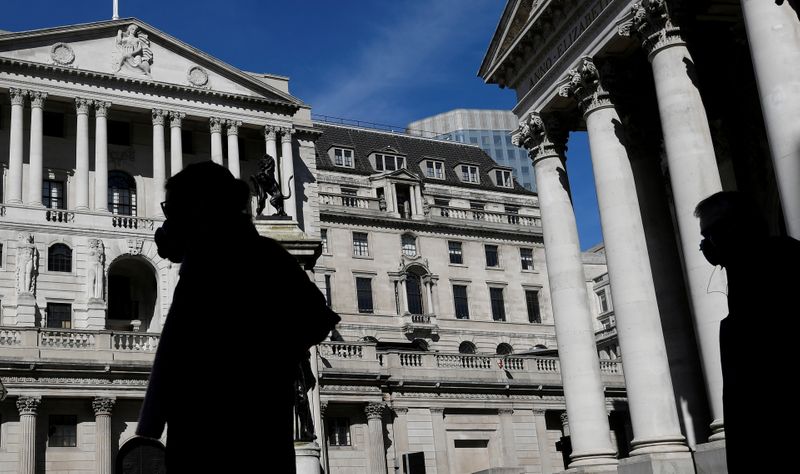 FILE PHOTO: People wearing masks walk past the Bank of