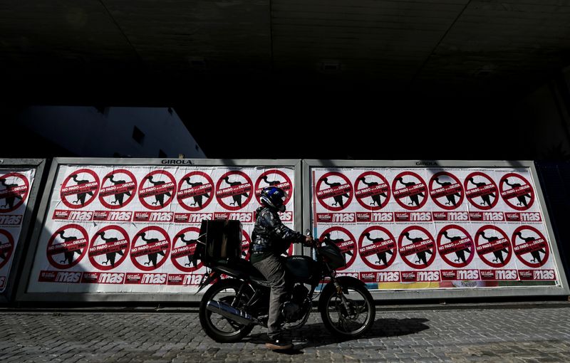 FILE PHOTO: A motorcyclist drives his motorbike past posters on