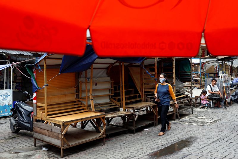 A woman wearing a protective face mask walks past closed