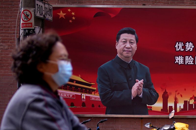 Woman is seen past a portrait of Chinese President Xi