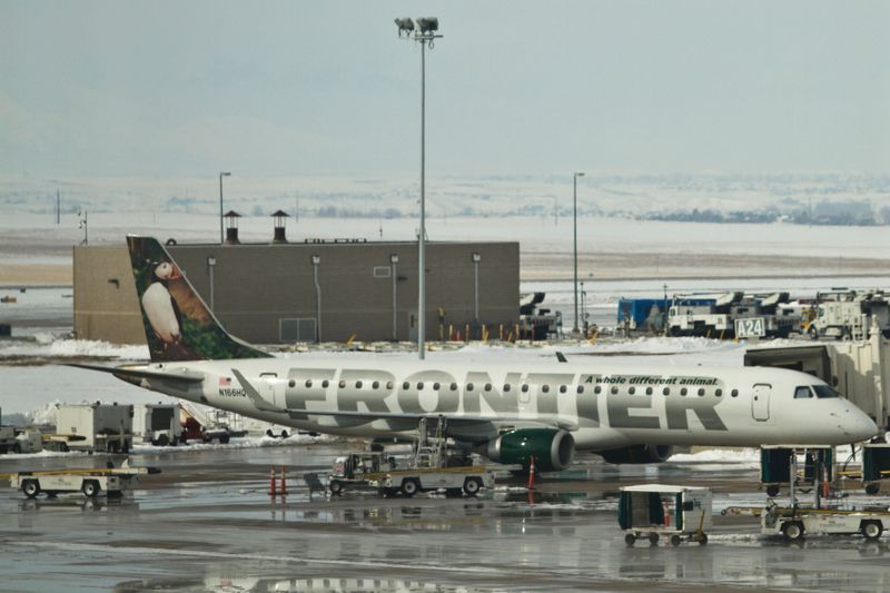 A Frontier Airlines jet waits at the gate prior to