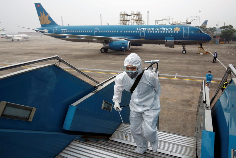 A health worker sprays disinfectant outside a Vietnam Airlines airplane