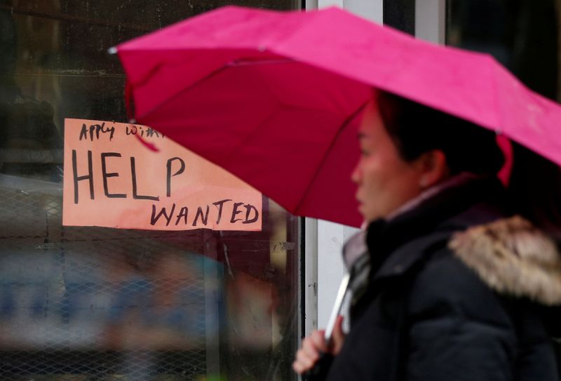 FILE PHOTO: A woman walks past a “Help wanted” sign