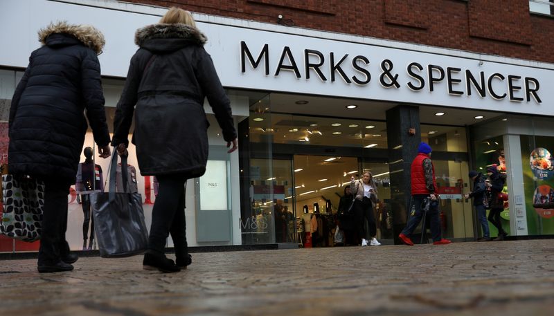 FILE PHOTO: Shoppers walk past a branch of Marks and