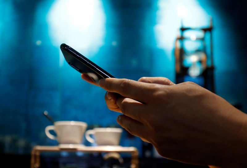 A man uses a mobile device in a coffee shop