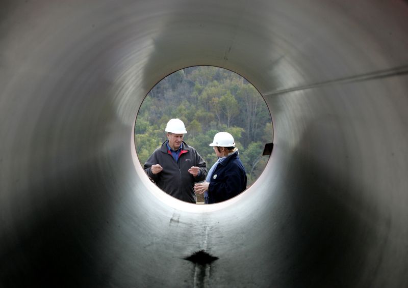 FILE PHOTO: Engineers talk standing next to pipes at a