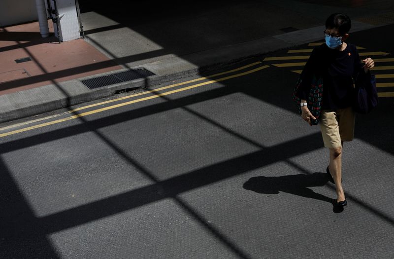 A woman wearing a protective face masks crosses a street,