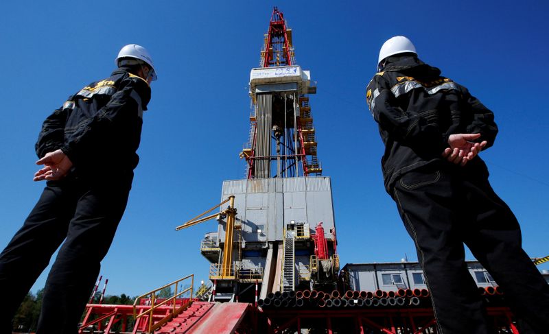 FILE PHOTO: Workers look at a drilling rig of the