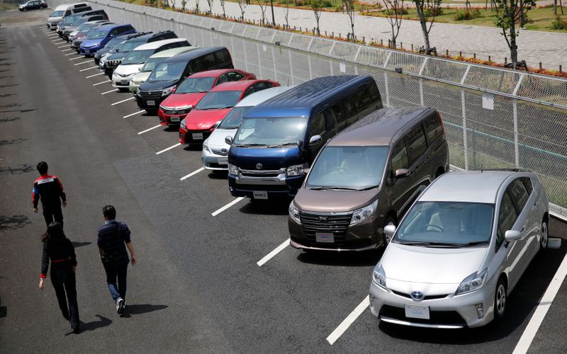 FILE PHOTO:  People walk beside test-driving cars outside a