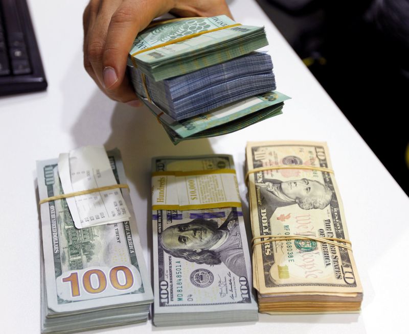 FILE PHOTO: A man holds Lebanese pounds next to U.S.