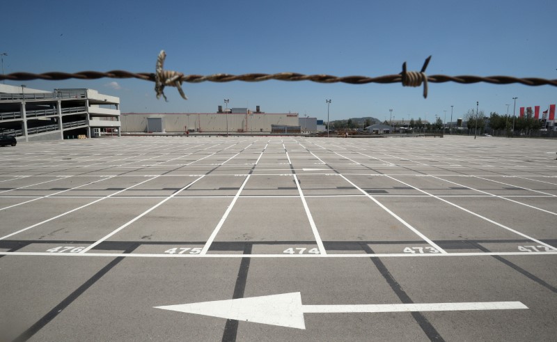 An empty parking lot is seen through a fence at