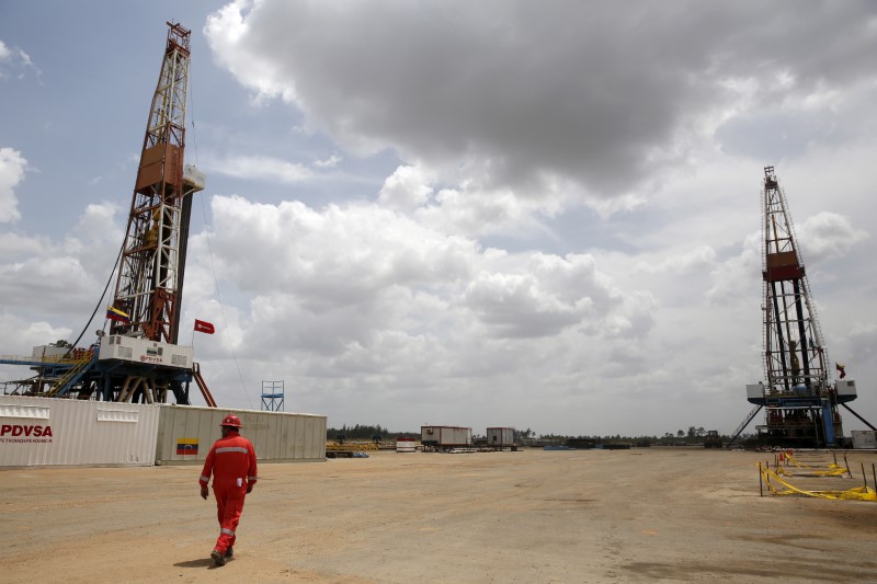 FILE PHOTO: An oilfield worker walks next to drilling rigs