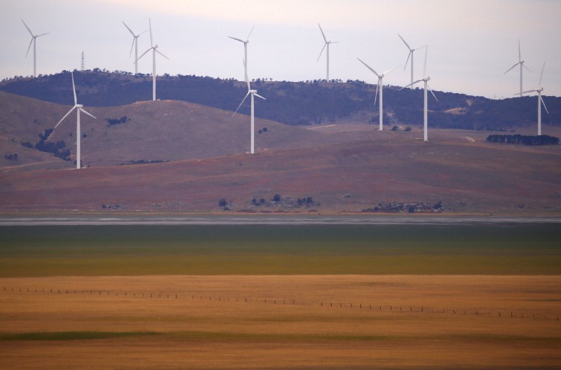 A fence is seen in front of wind turbines that