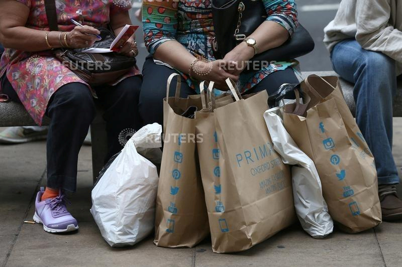 FILE PHOTO: Shoppers sit with bags in London