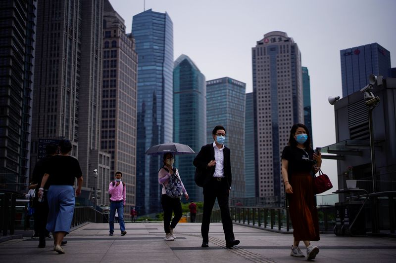 People wearing protective face masks walk past office buildings in