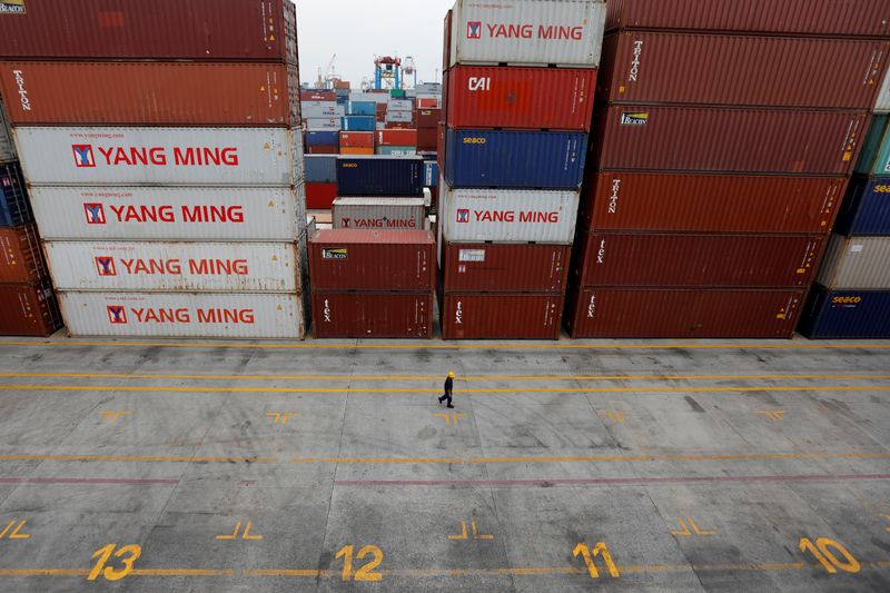 A worker passes stacks of containers at Tanjung Priok port