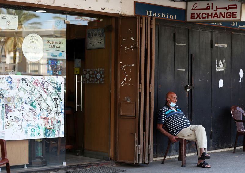 FILE PHOTO: A man sits outside of a currency exchange
