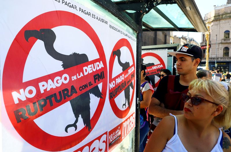 FILE PHOTO: Pedestrians walk past posters on the streets that