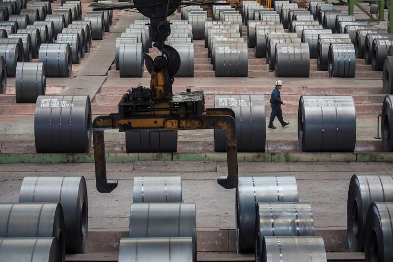 Worker walks past steel rolls at the Chongqing Iron and