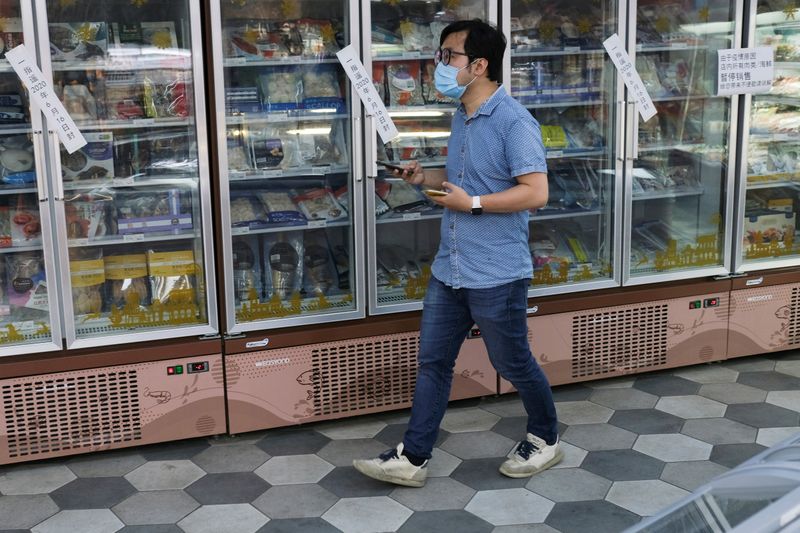 FILE PHOTO: Man walks past sealed freezers containing seafood products