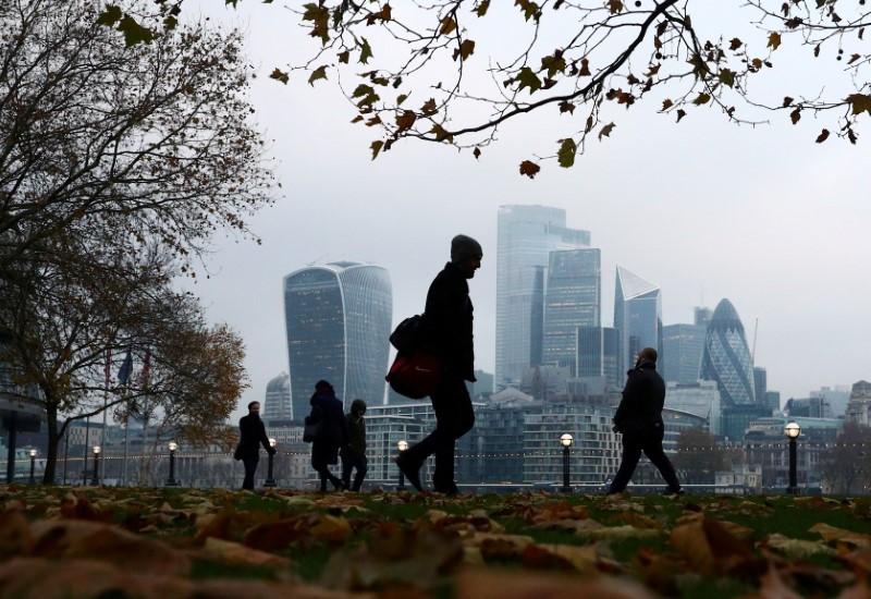 FILE PHOTO: People walk through autumnal leaves in front of