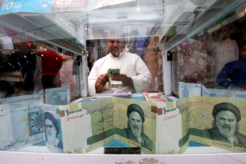 FILE PHOTO: A man counts Iranian rials at a currency